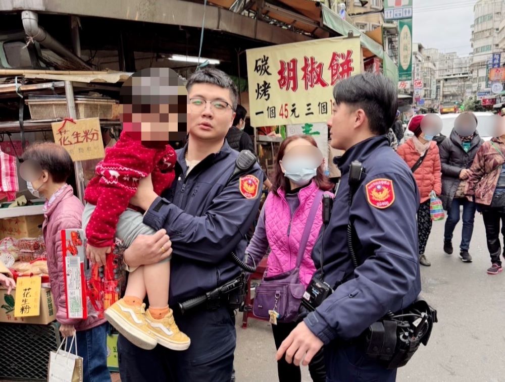 《圖說》海山分局江翠所員警李祁彥、林孟煇抱著小男童於市場內協尋家屬。〈海山分局提供〉