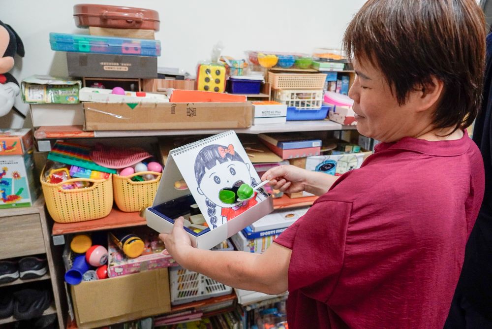 減輕家屬負擔 新北推動身心障礙者家庭托顧服務 1 《圖說》董珮彤自製道具輔助教學,如吃水果圖卡,讓孩子練習夾入口中 以此訓練飲食的情境。〈社會局提供〉