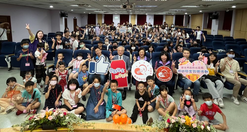 《圖說》新北市不動產開發商業同業公會捐贈獎助學金支持新北弱勢學生安心就學，社會局今日舉辦頒贈活動，國小生至大學生及家長近百位齊聚合影。〈社會局提供〉