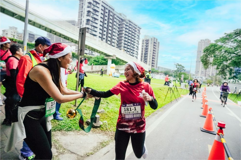 《圖說》揹上巨型鈴鐺接力信物跑遍耶誕城--113年資料照。〈觀旅局提供〉