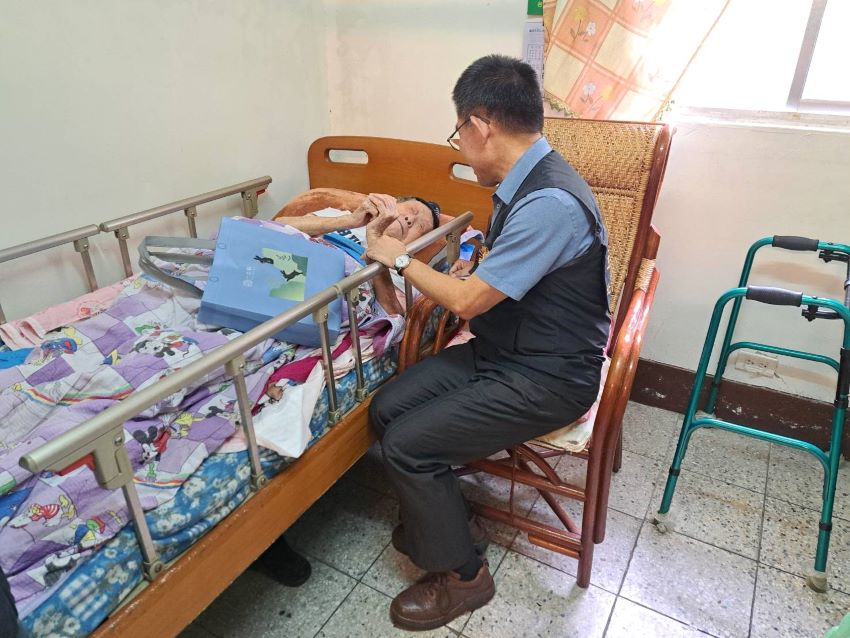 《圖說》台北榮服處長黃信仁關懷單身特需照顧躺床的榮民鄭華興。〈台北榮服處提供〉