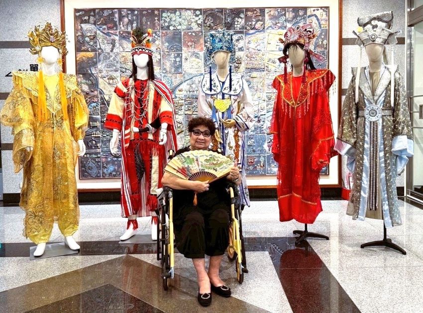 《圖說》「2025新莊有好戲」系列活動，今日起於新莊文化藝術中心推出《明雪璀璨映戲臺──藝師洪明雪片段記事》特展，圖為洪明雪藝師與她親手縫製、實際穿戴過的戲服。〈文化局提供〉